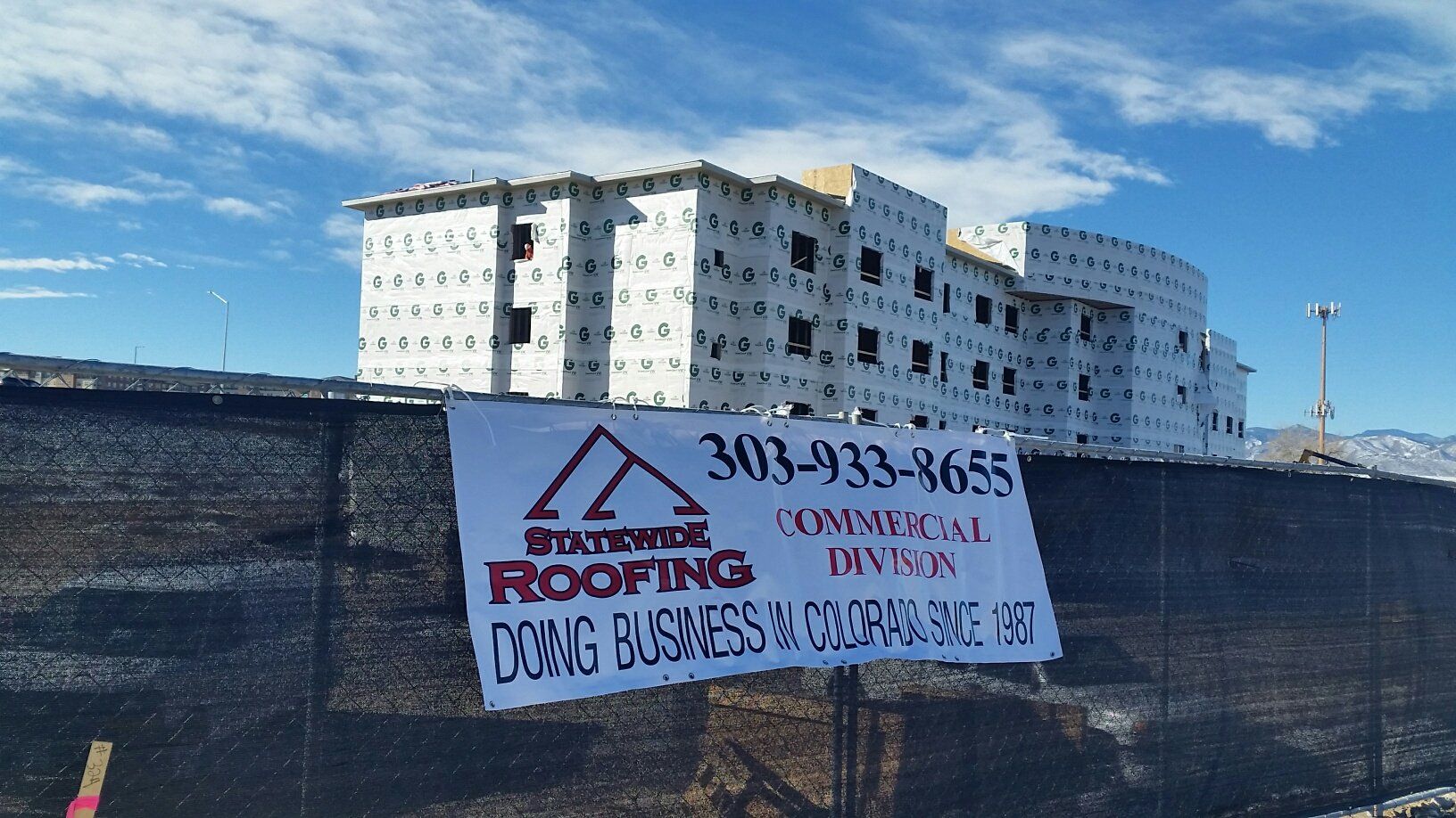 a building under construction with a roofing sign in front of it