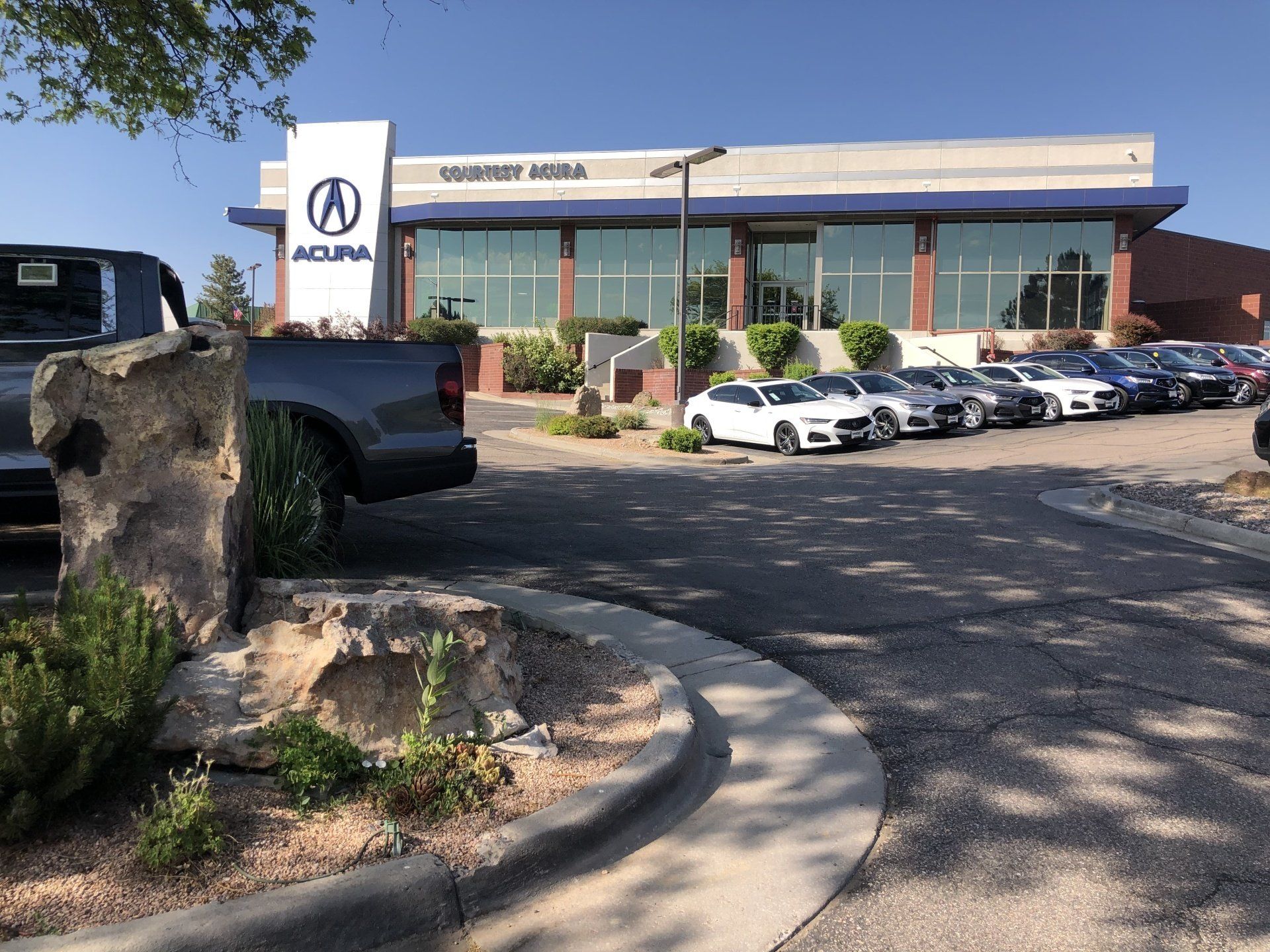 a row of cars are parked in front of an acura dealership .