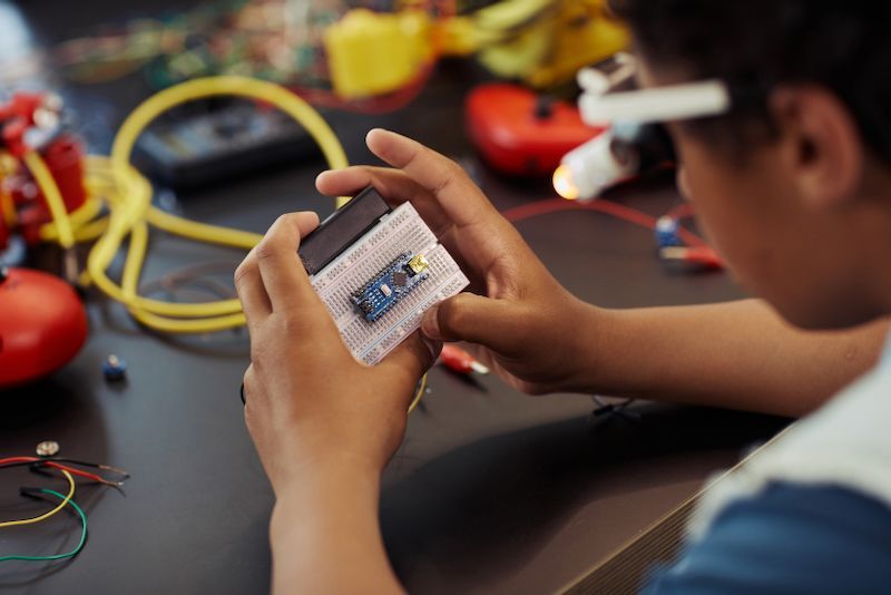 A young boy is holding a small electronic device in his hands.