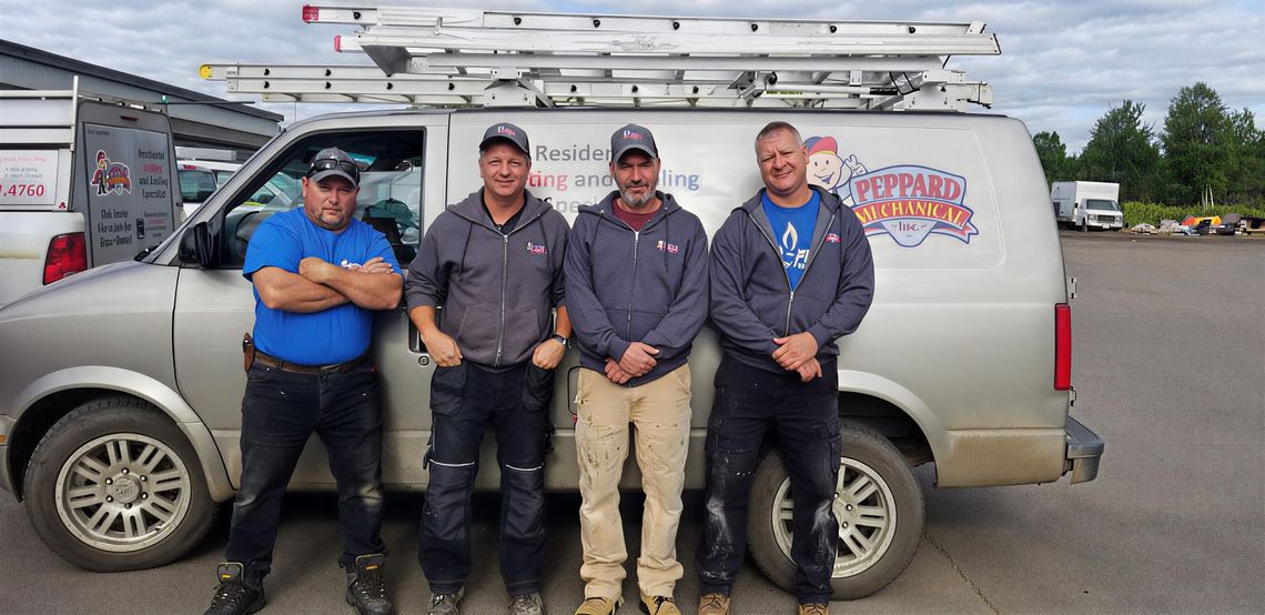 Four men pose in front of a van. The van has ladders on top and a logo on the side that reads D. Peppard Mechanical Inc.