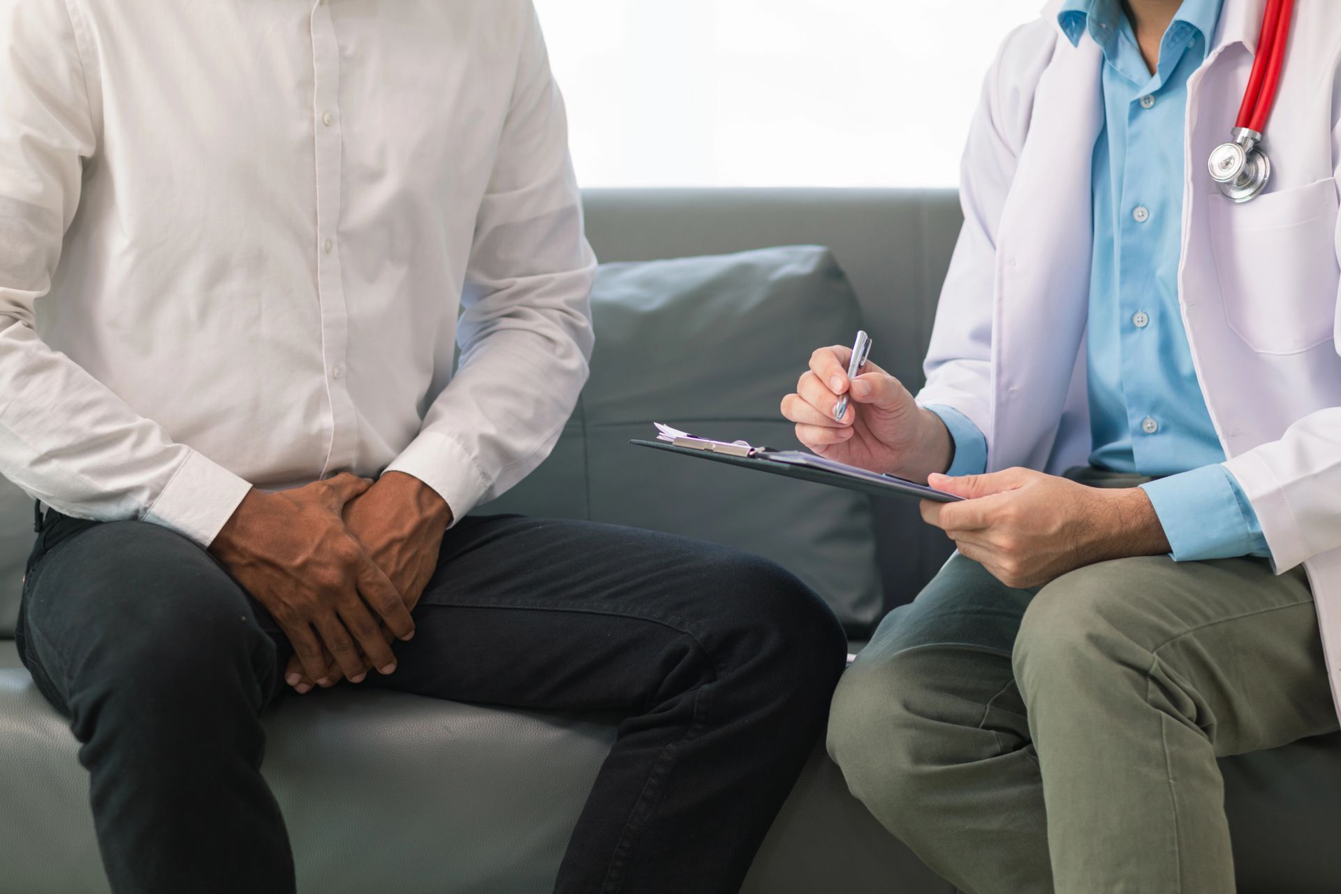 Un médico está hablando con un paciente que está sentado en un diván.