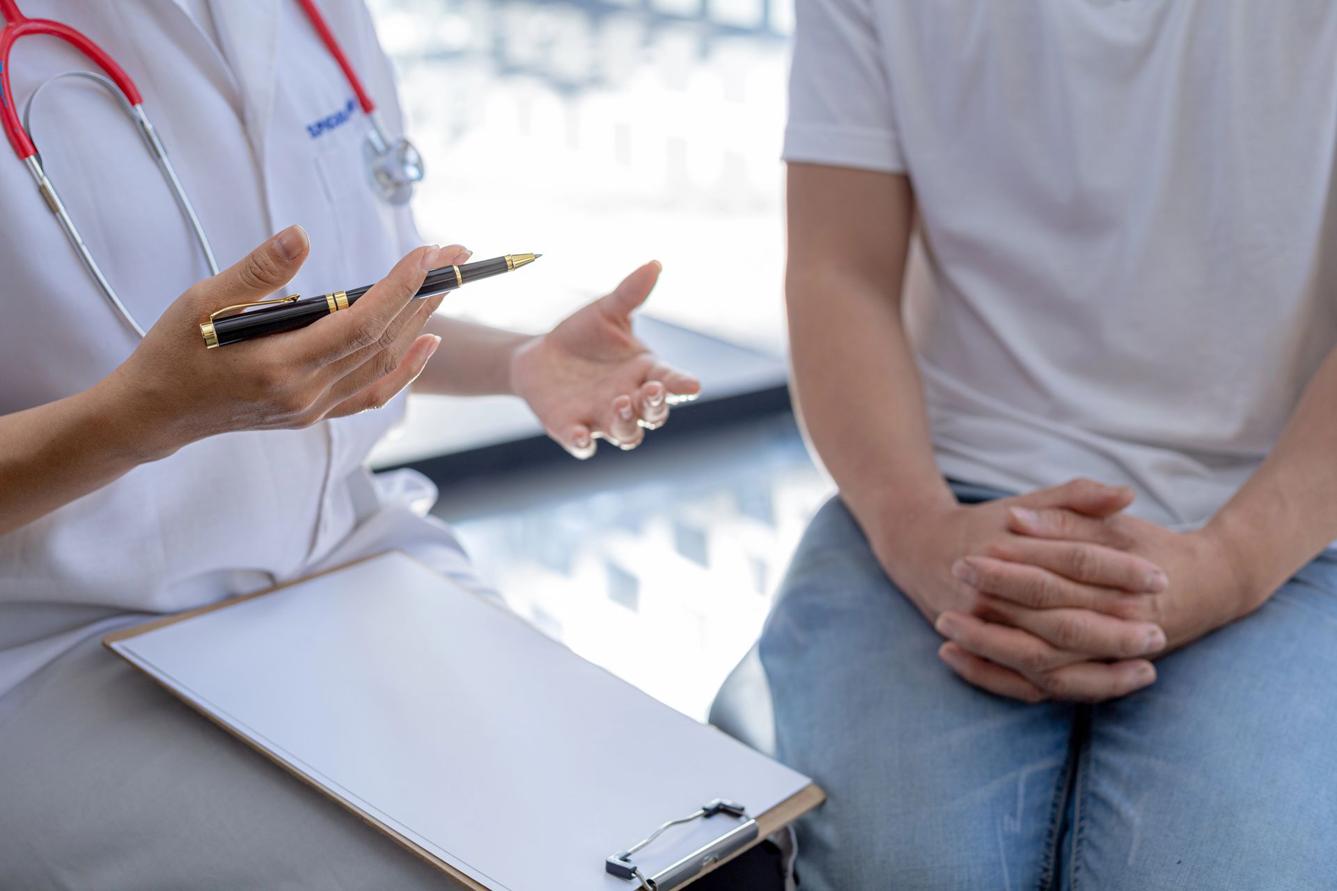 Un médico está hablando con un paciente que está sentado.