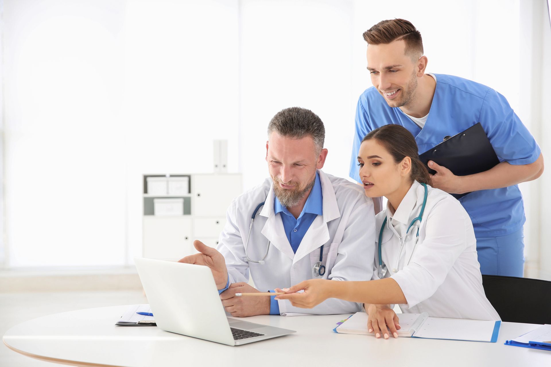Un grupo de médicos está mirando una computadora portátil.