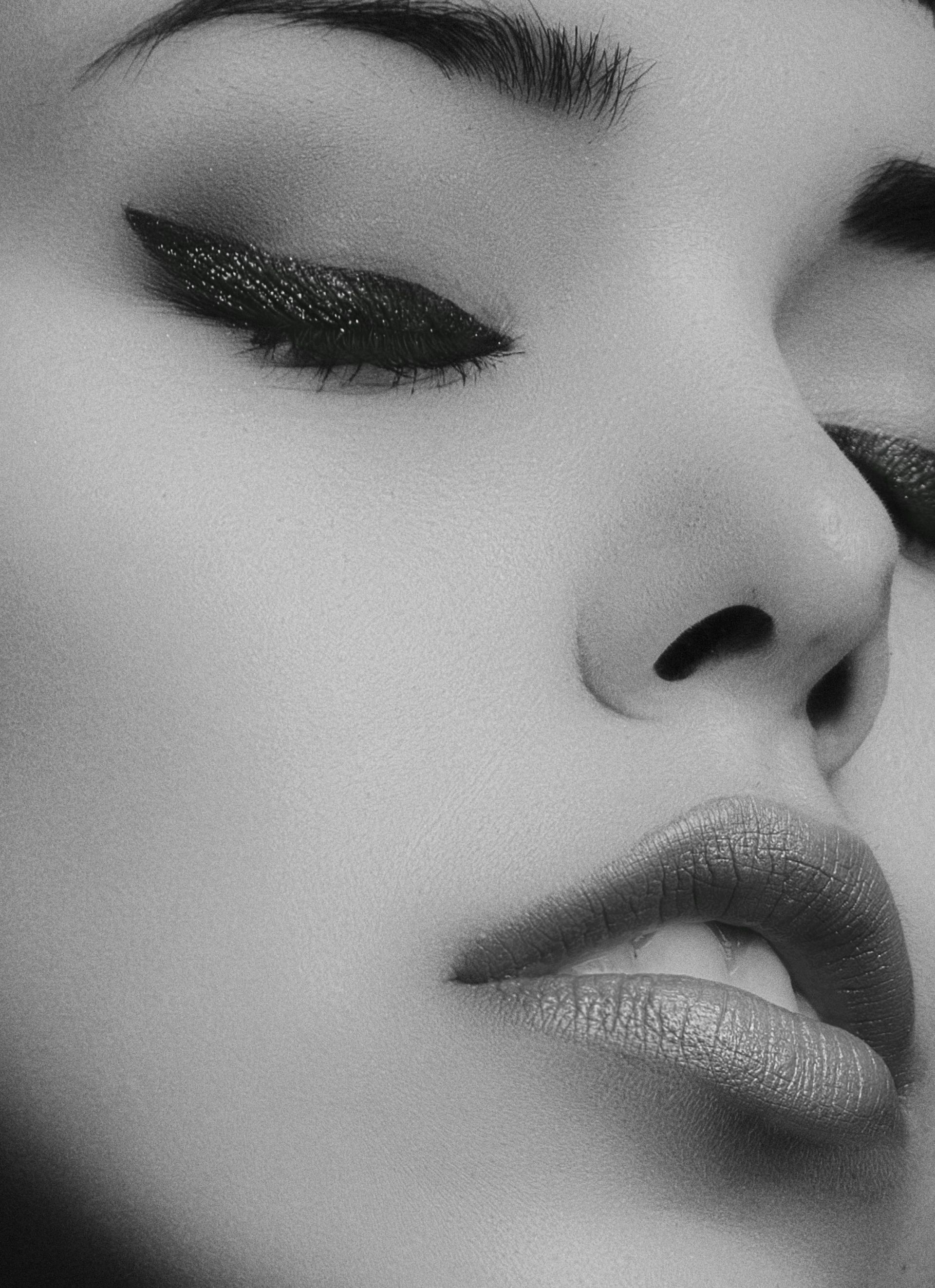 A black and white photo of a woman 's face with her eyes closed.