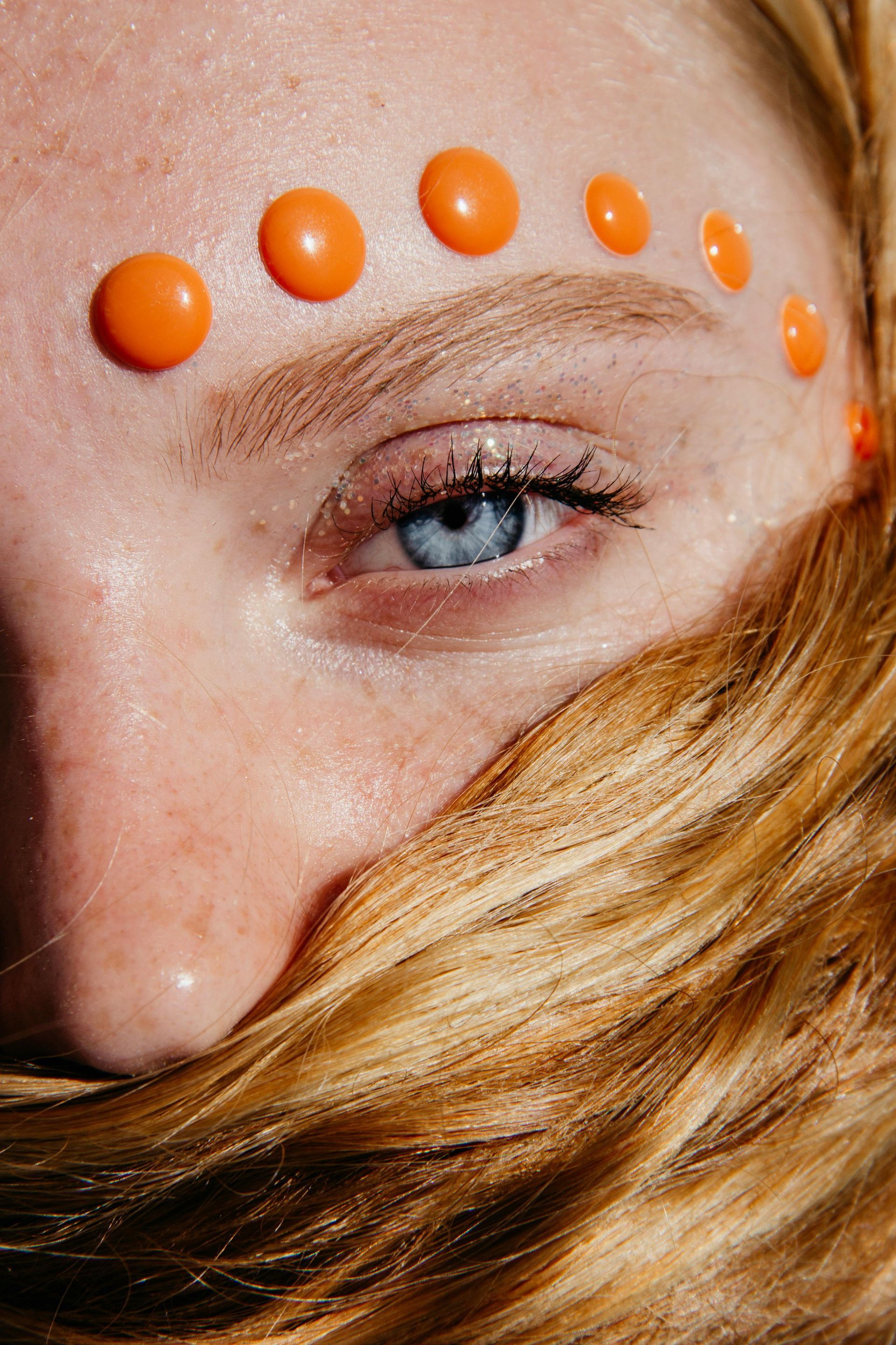 A close up of a woman 's face with orange circles on her forehead.