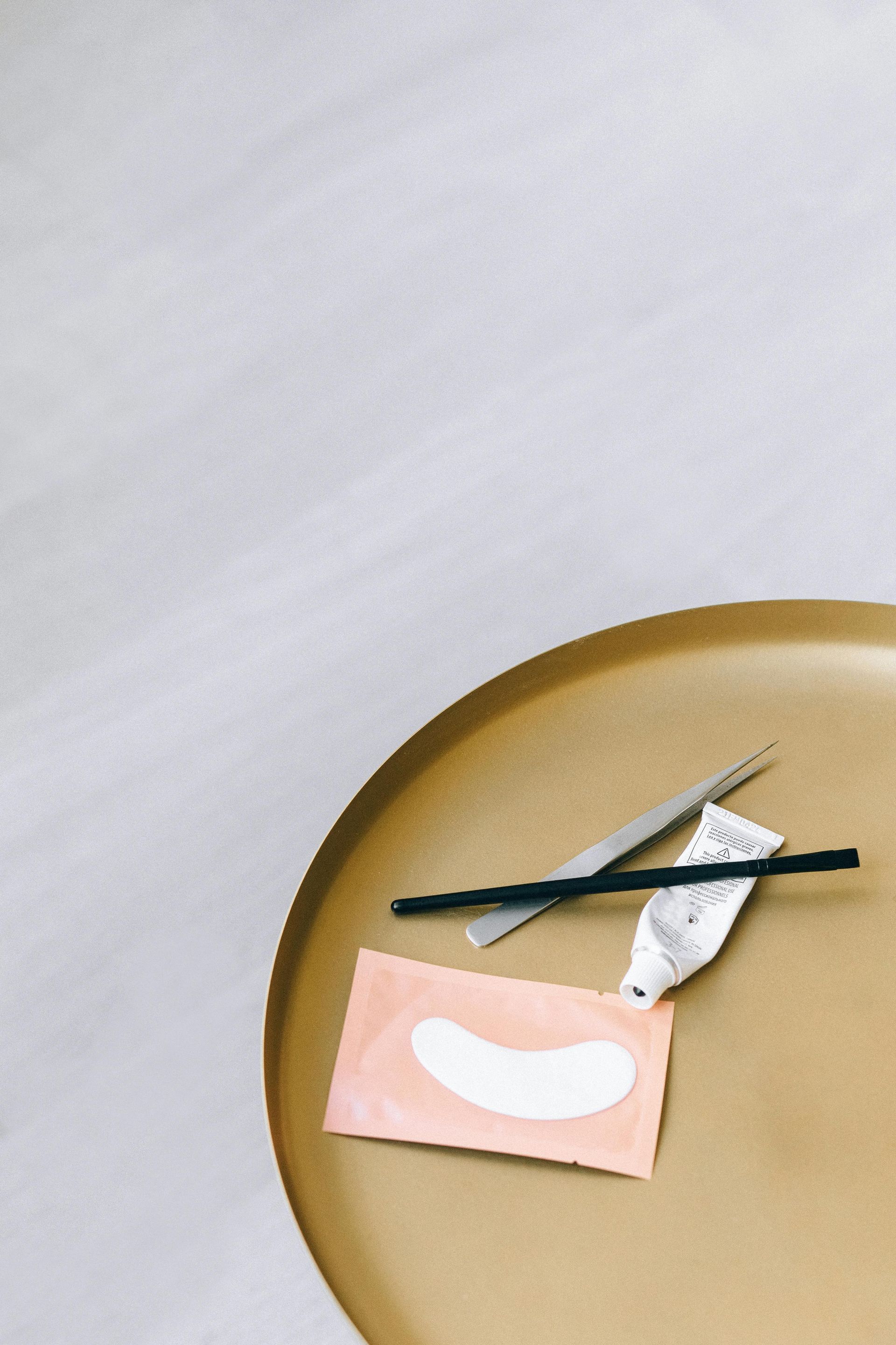 A table with a brush , tweezers , and eye patches on it.