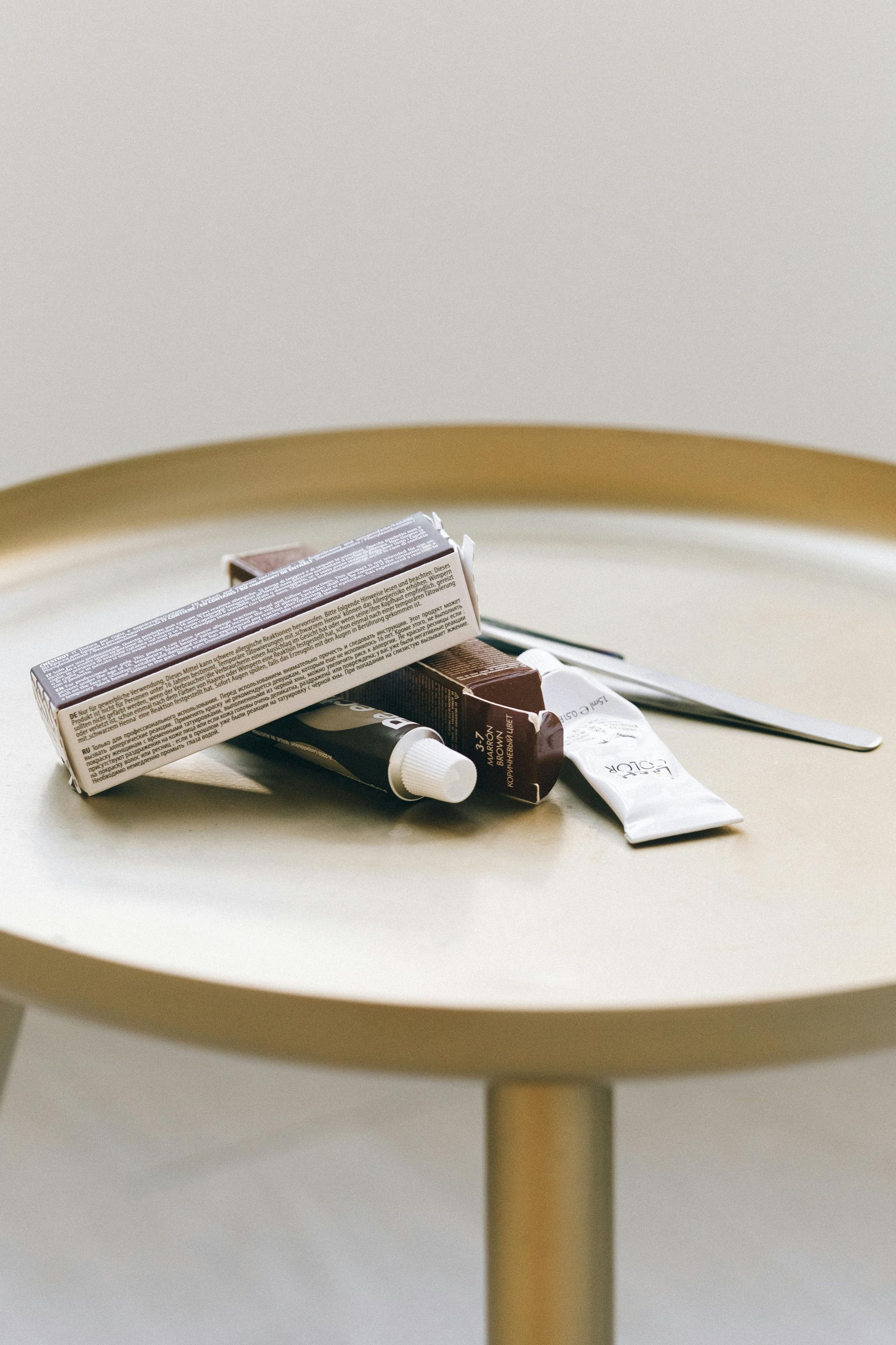 A table with a stack of lipsticks and a pair of scissors on it.