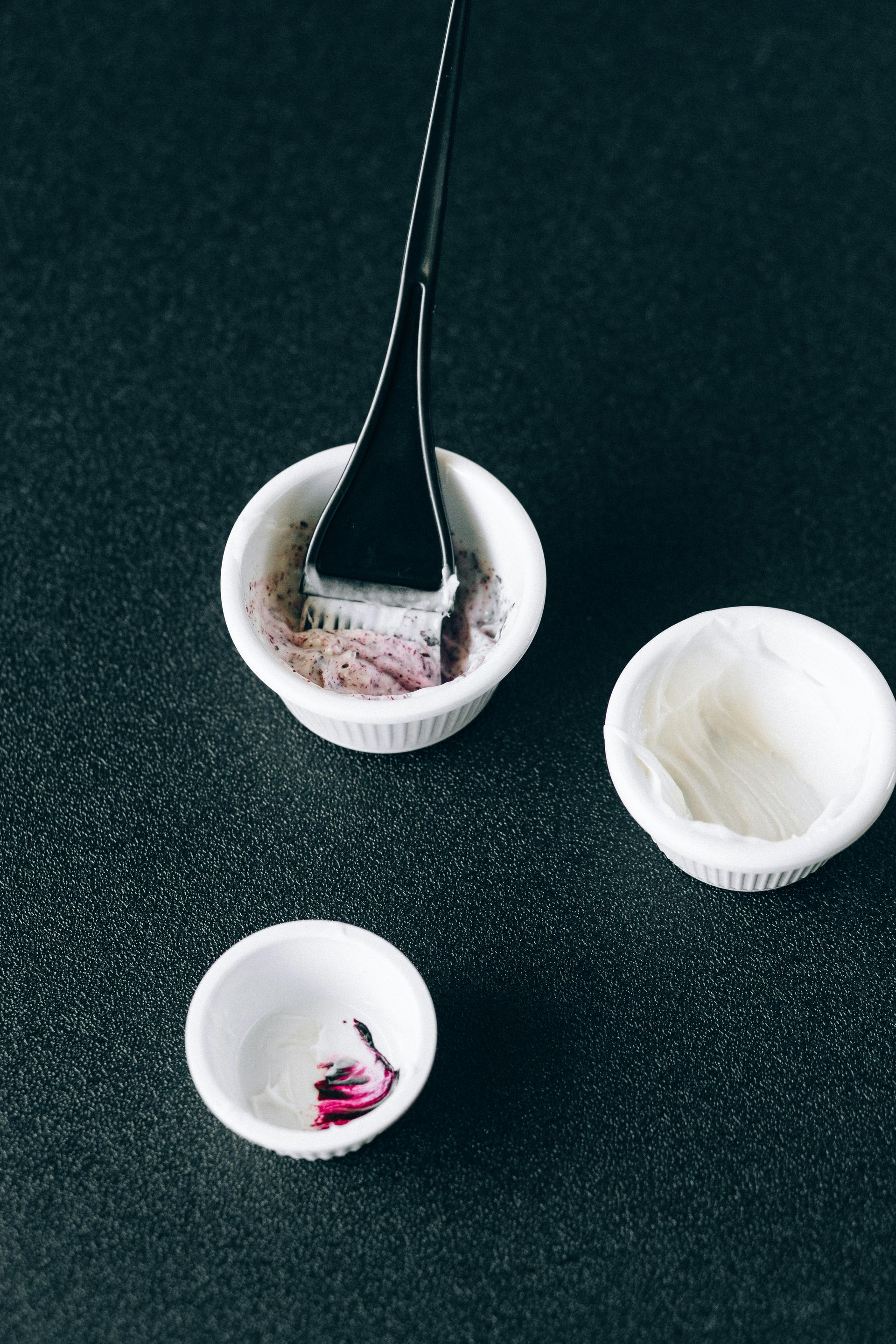 A bowl with a brush in it and two small bowls on a table.