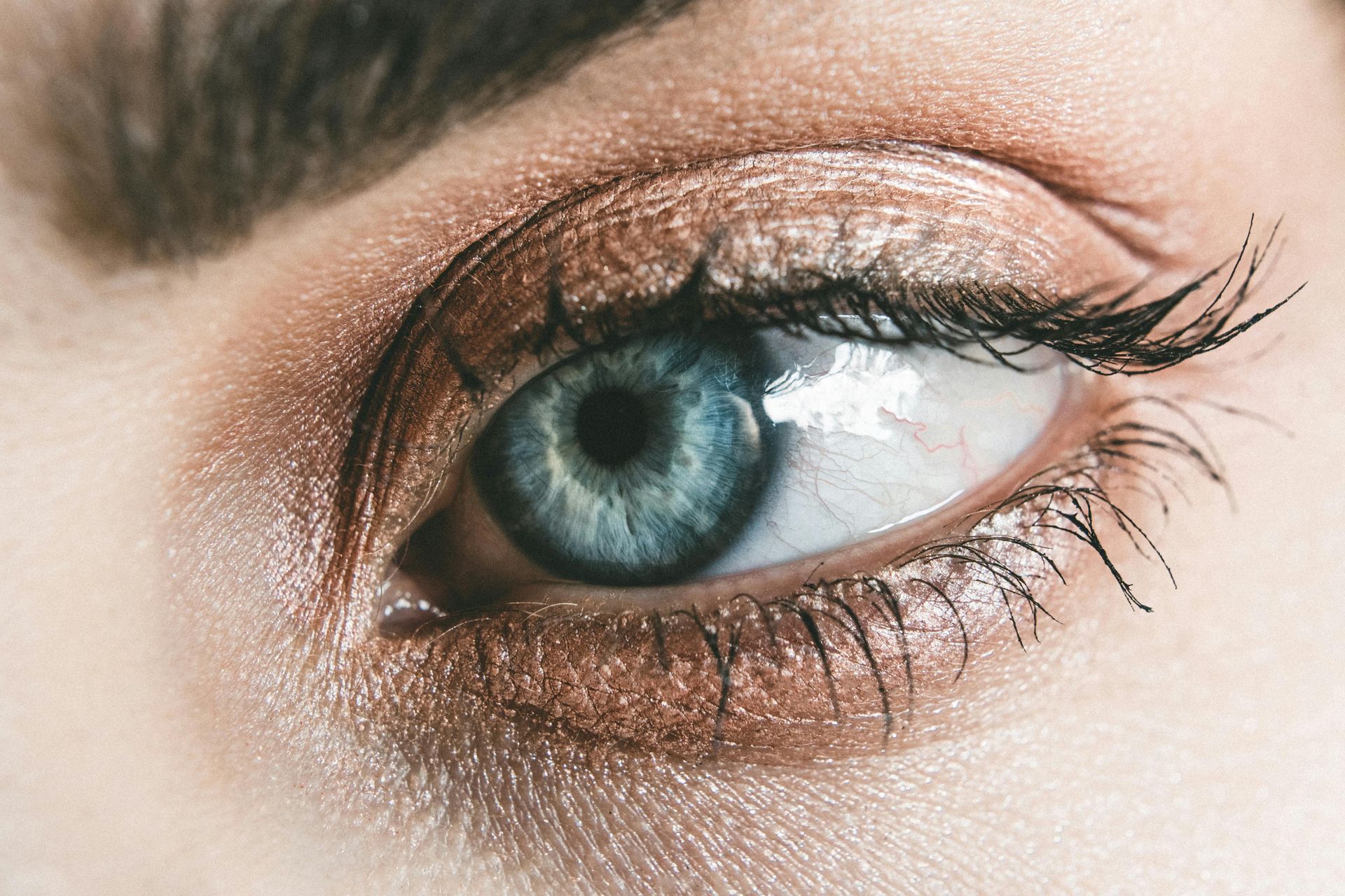 A close up of a woman 's blue eye with brown eyeshadow.