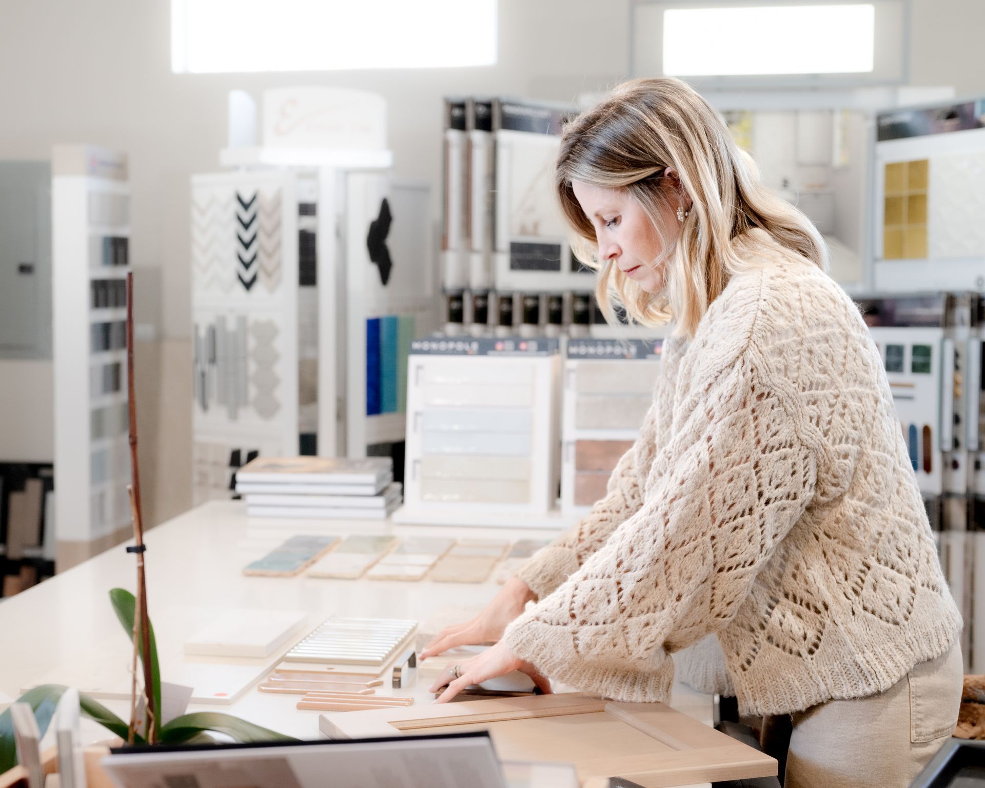 Woman in beige sweater examines samples at a design studio.