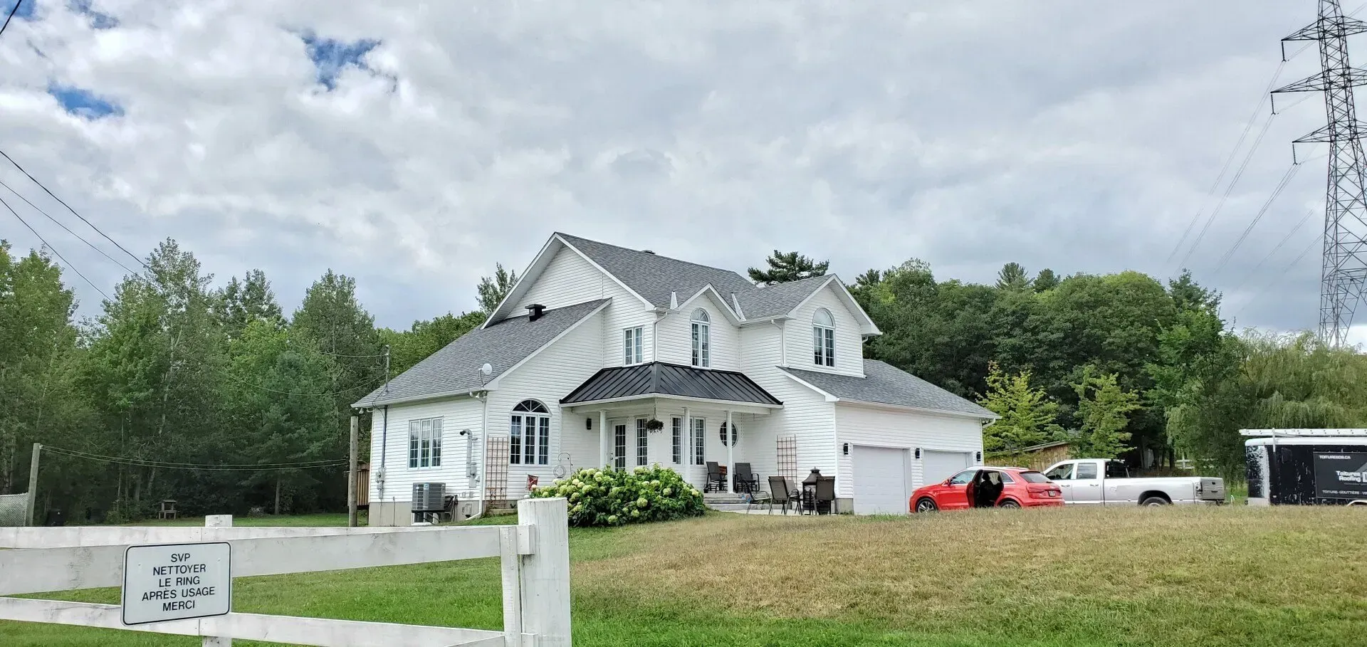 Une grande maison blanche est assise au milieu d'un champ herbeux.