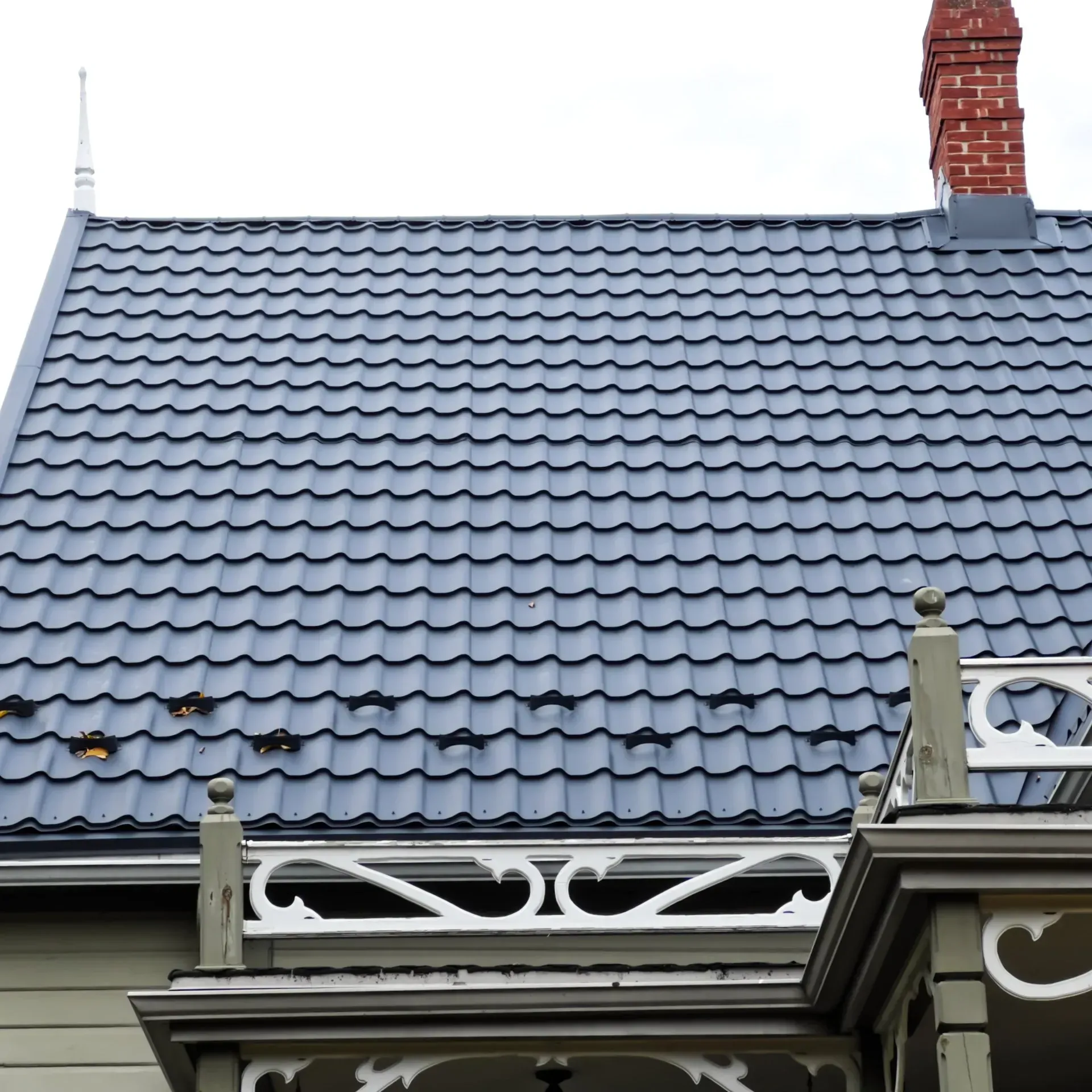 Une maison avec un toit de tuiles bleues et une cheminée en brique