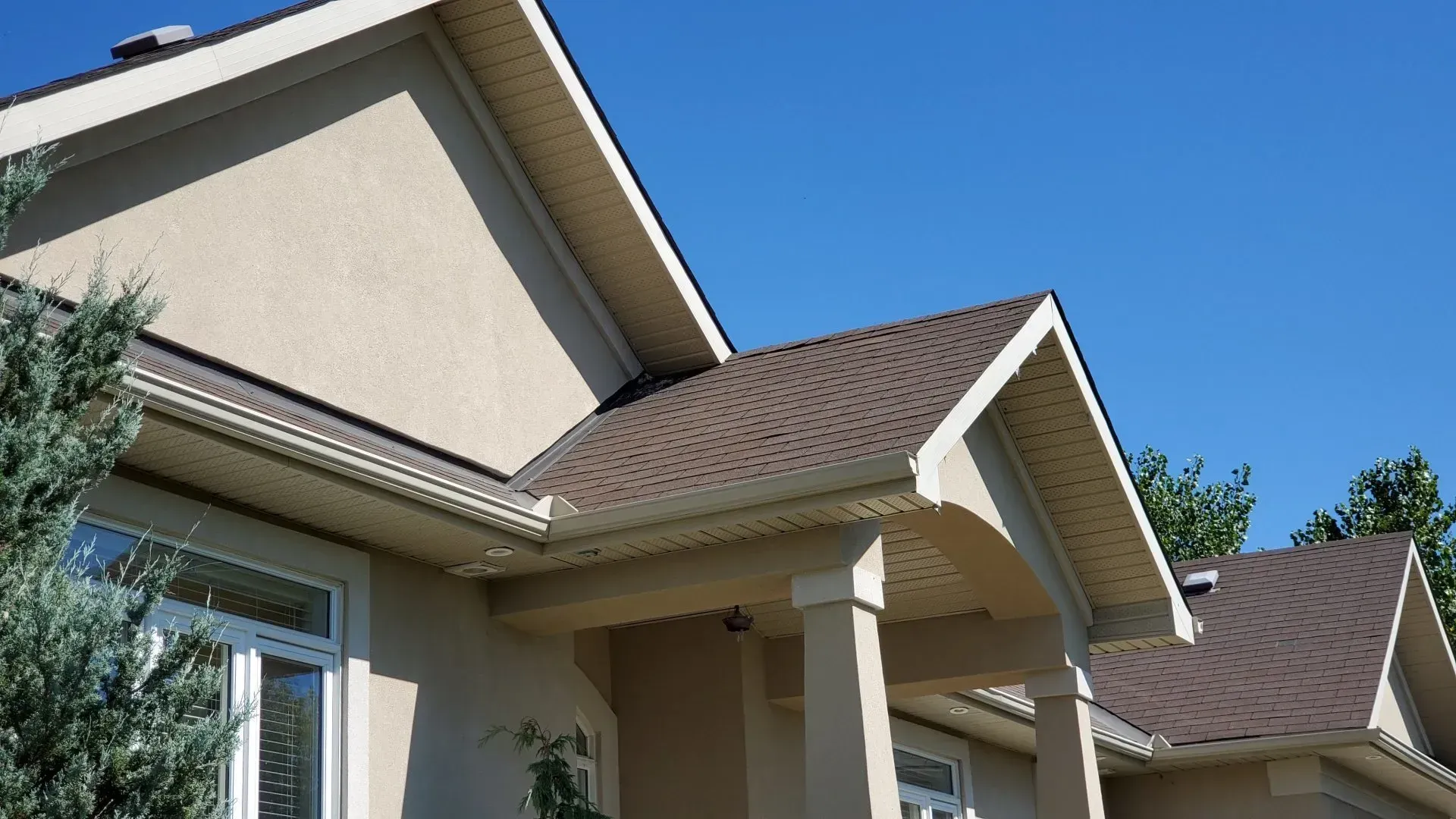 Une maison avec un toit marron et un porche par une journée ensoleillée.