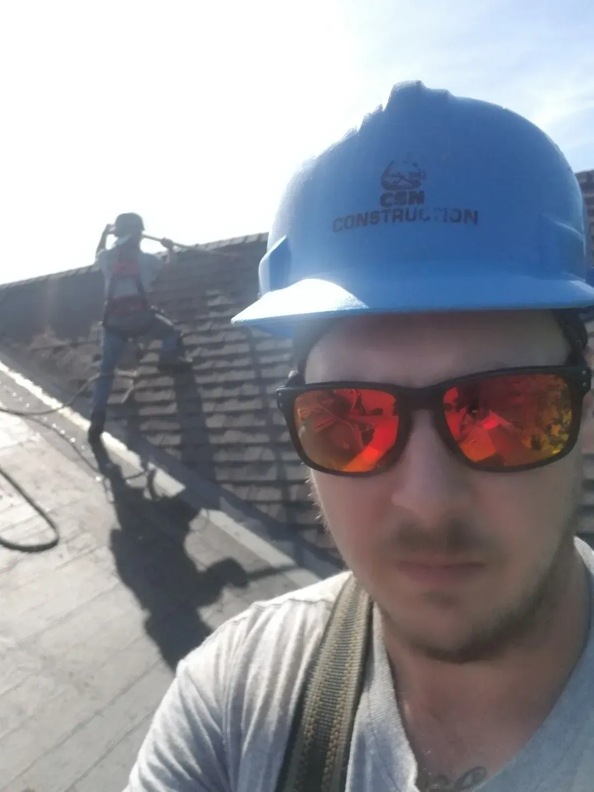 Un homme portant des lunettes de soleil et un casque de construction bleu