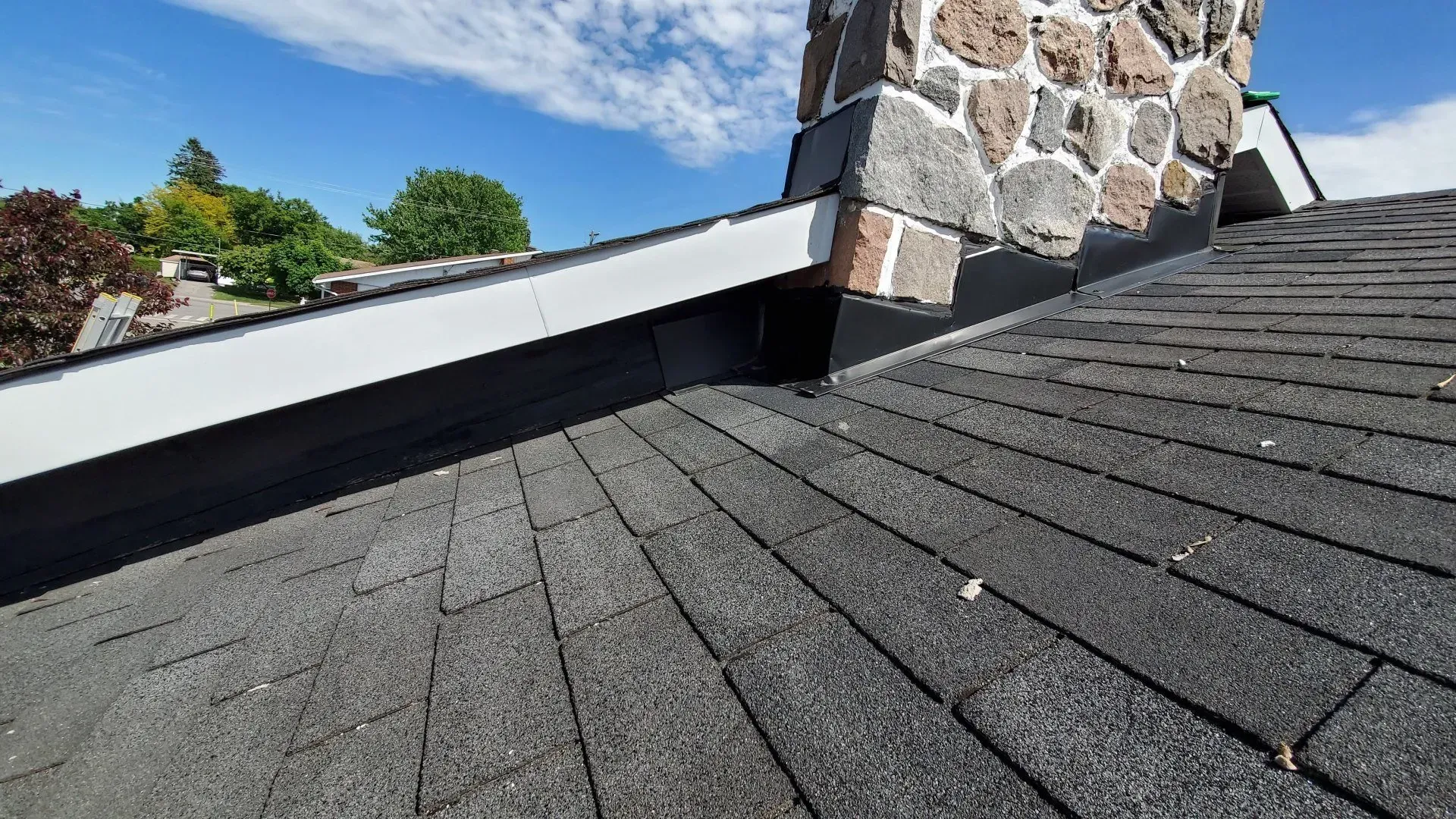 Un gros plan d'un toit avec une cheminée en arrière-plan.