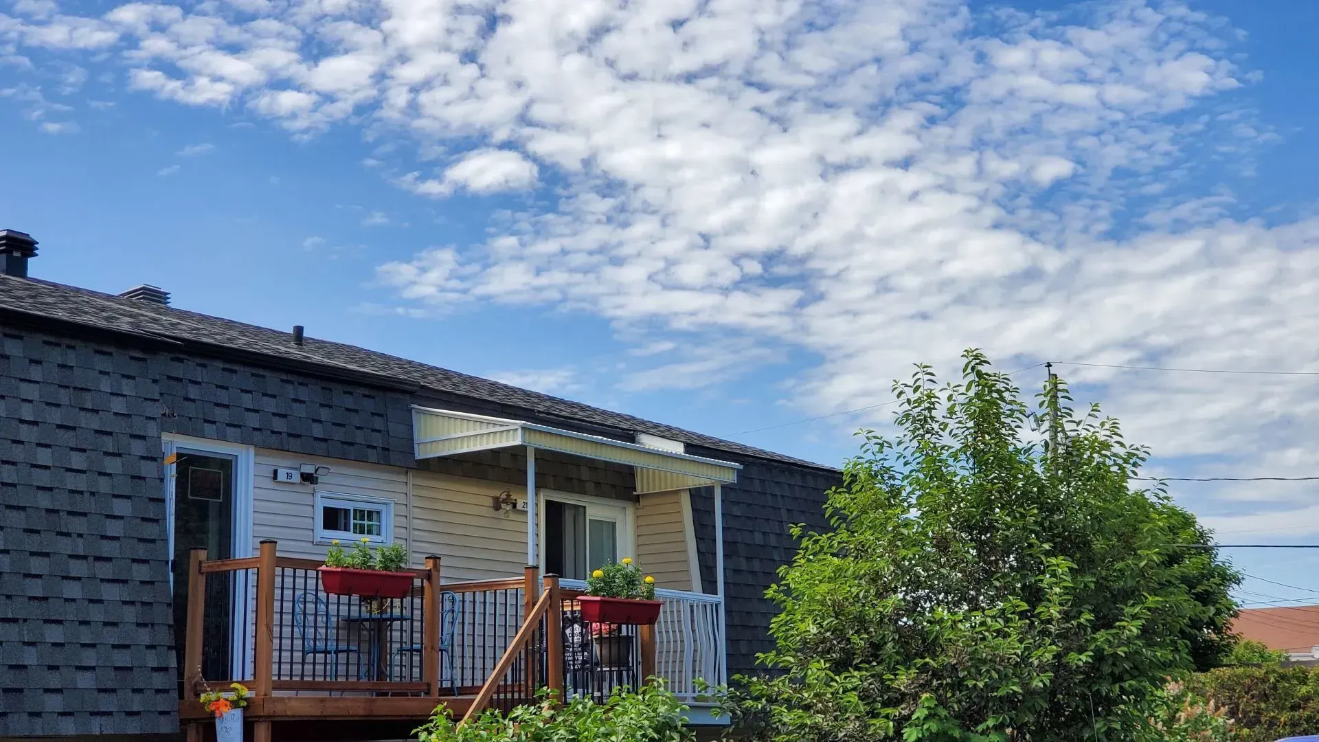 Une maison avec une grande terrasse et un ciel bleu en arrière-plan.