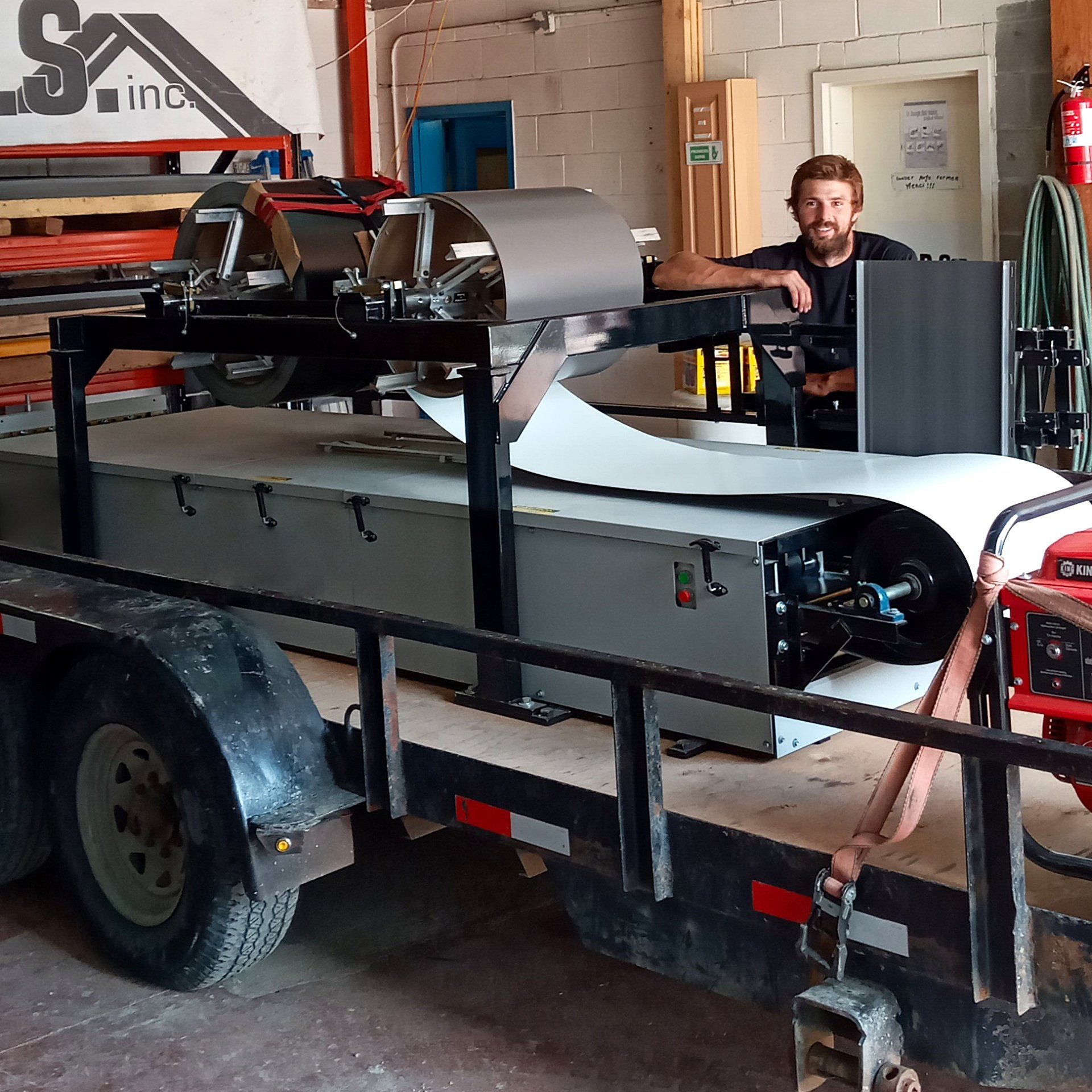 Un homme est assis derrière une machine sur une remorque qui dit sa inc.