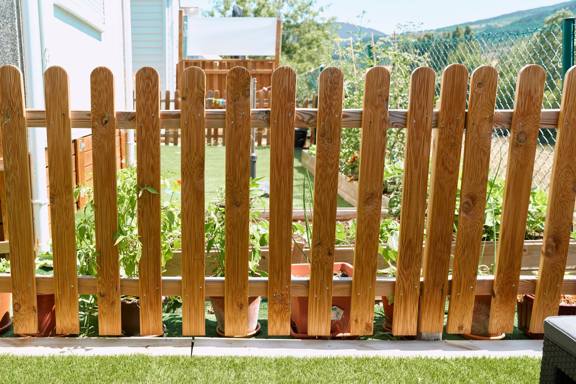 A wooden picket fence is sitting on top of a lush green lawn.