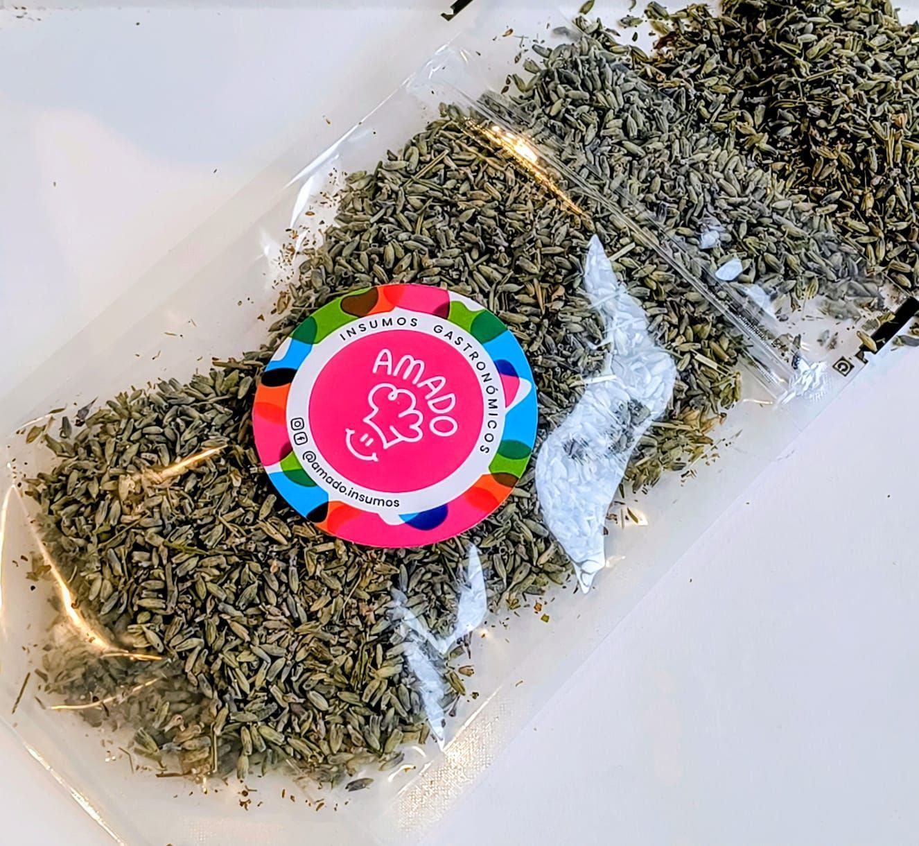Capullos de lavanda en una bolsa de plástico transparente con una etiqueta circular de colores que dice "Amado Curandero".