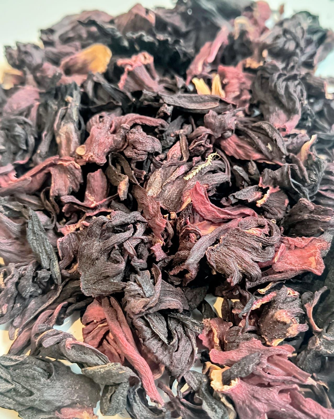 Bolsa de plástico transparente con flores de hibisco rojo secas y una etiqueta colorida que dice