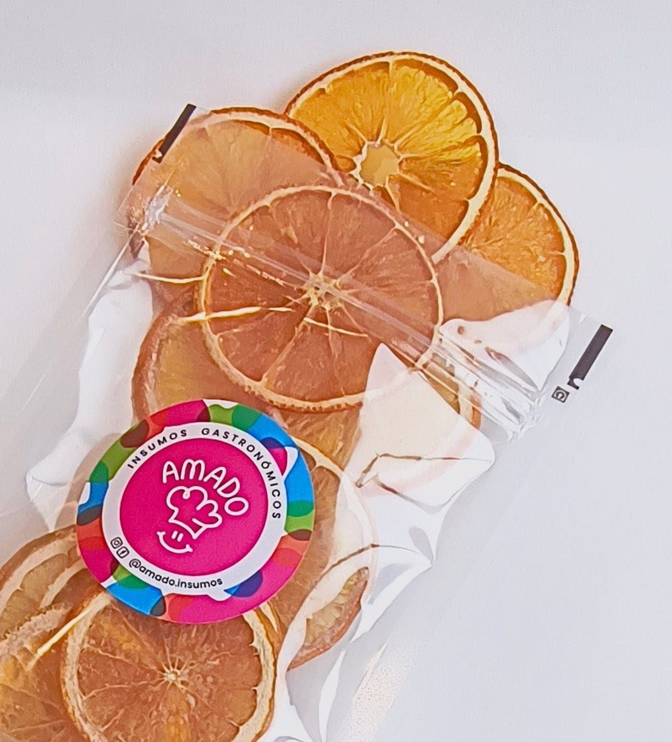 Rodajas de naranja secas en una bolsa de plástico transparente con una etiqueta redonda y colorida.