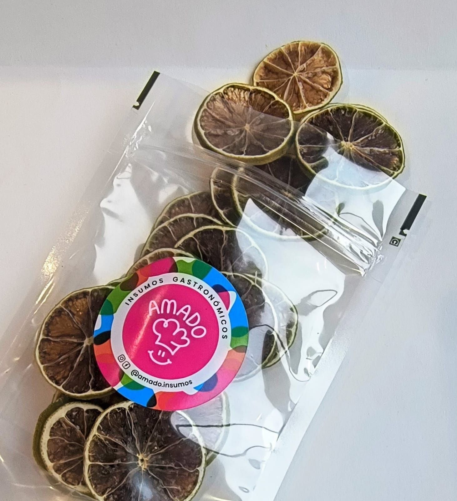 Bolsa de rodajas de lima secas con una pegatina de color sobre una superficie blanca.