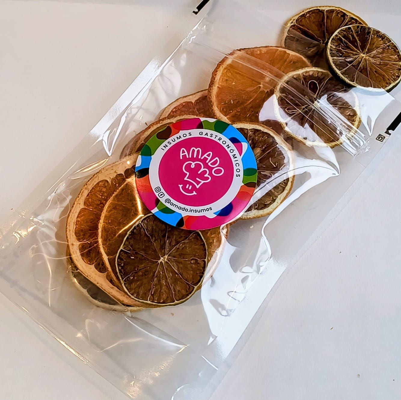 Rodajas de naranja y lima secas en una bolsa de plástico transparente con una pegatina con el logotipo.