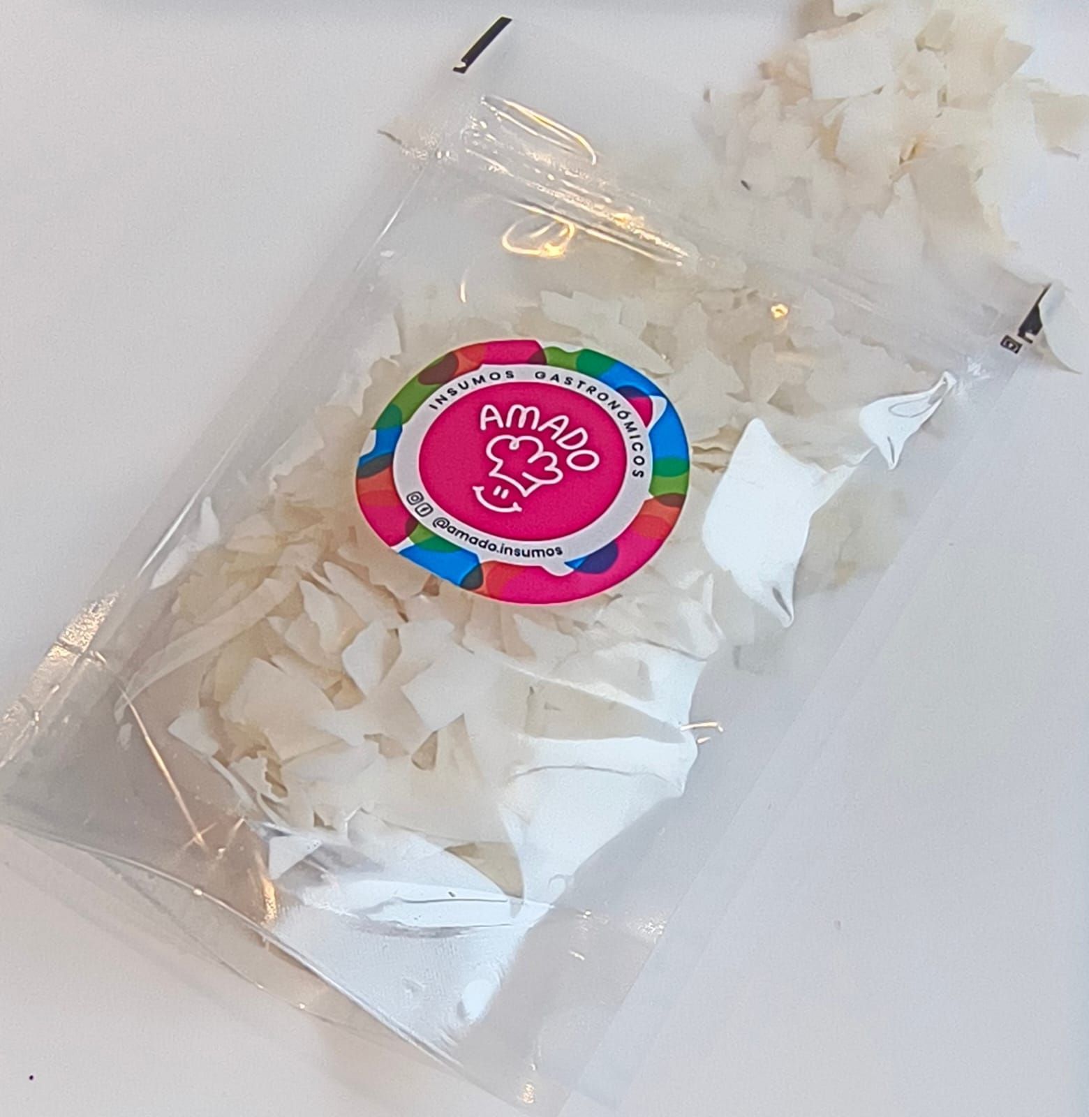 Bolsa de producto alimenticio blanco triturado, con logo colorido, sobre superficie blanca.