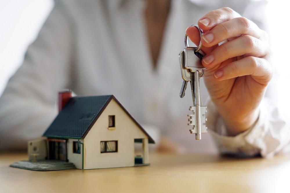 Woman Holding A Pair Of Keys In Front Of A Model House — Pro Vision Property Inspections In Merewether, NSW