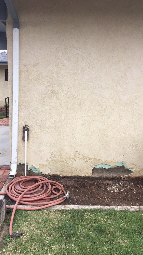 A hose is sitting on the side of a house next to a wall.