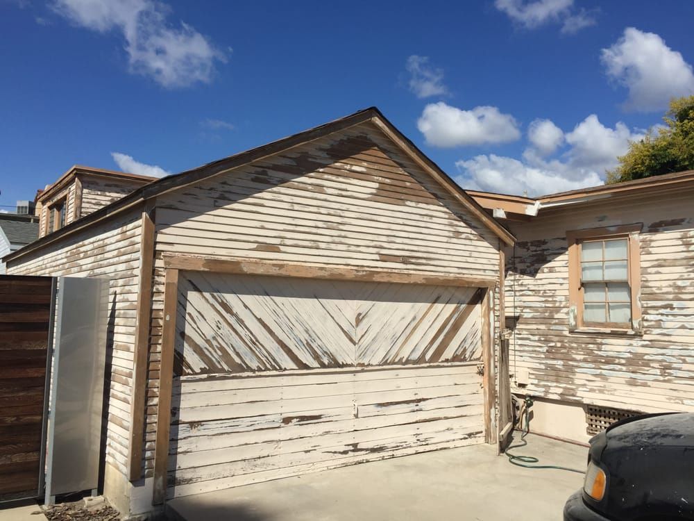 A car is parked in front of a house with a garage door