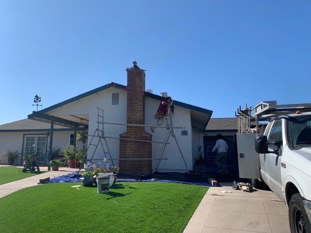 A white truck is parked in front of a house being painted.