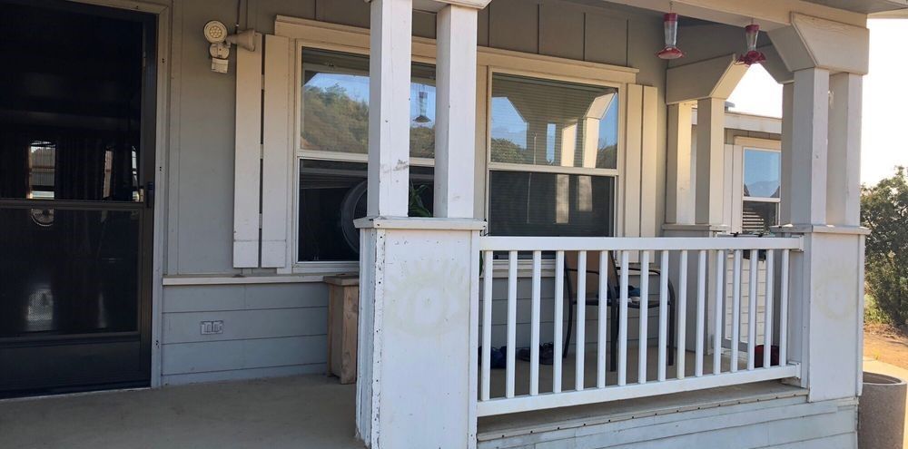 A porch with a white railing and a window on a house.