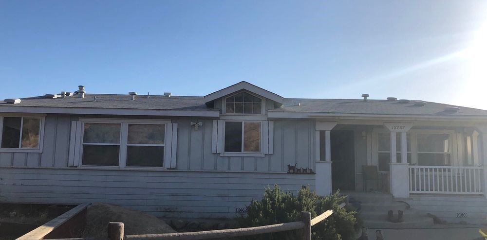 A white house with a fence in front of it and a blue sky in the background.