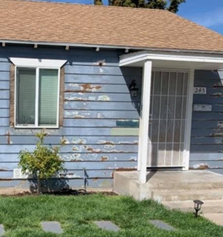 A blue house with a brown roof and a white door