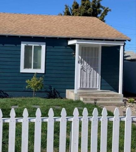 A blue house with a white picket fence in front of it.