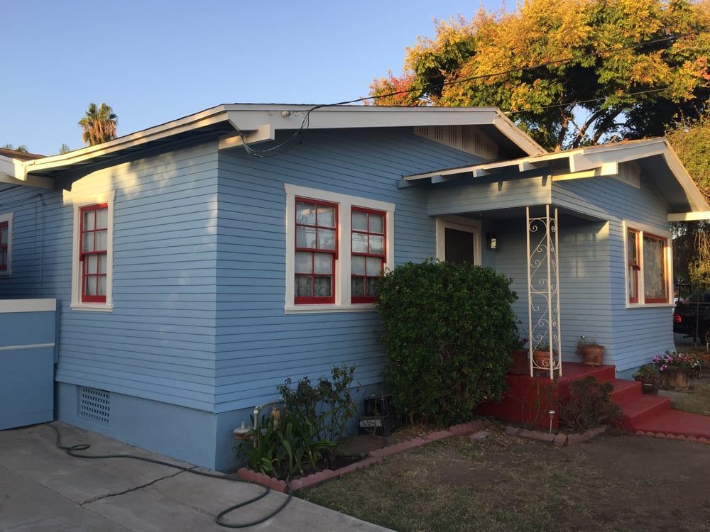 A blue house with white trim and red windows