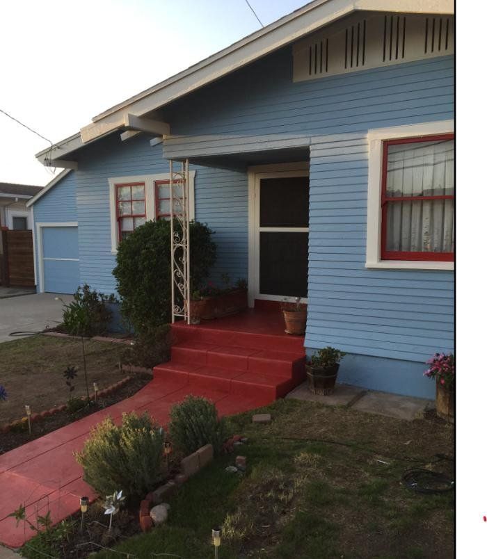 A blue house with red steps leading to the front door