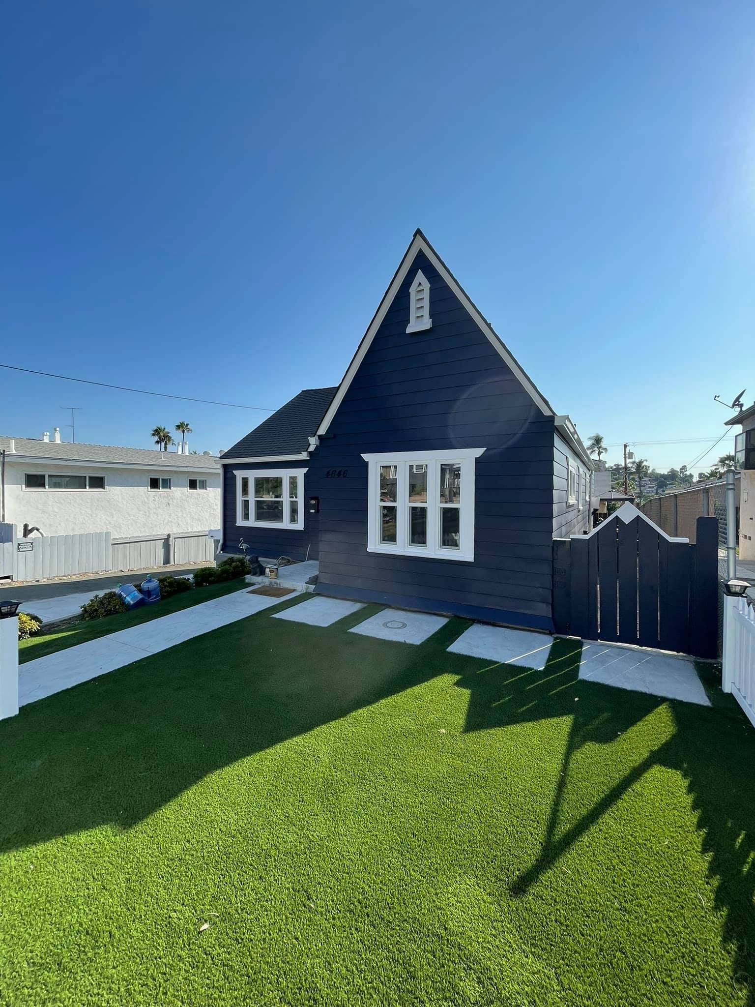 A black and white house with a lush green lawn in front of it.
