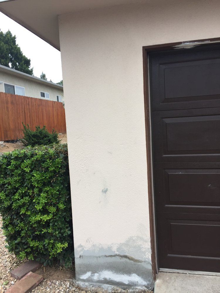 A brown garage door is next to a white wall