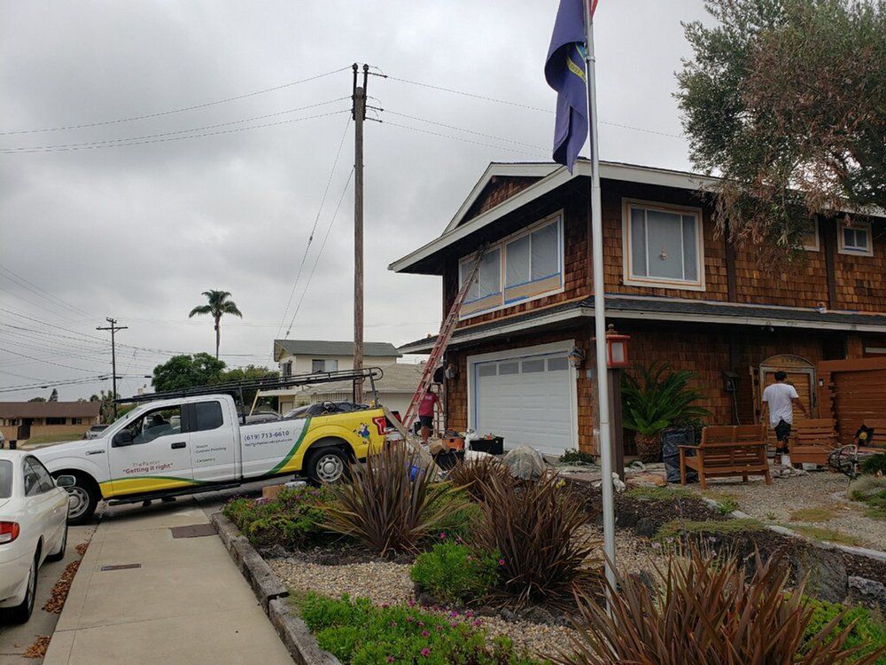 A yellow and white truck is parked in front of a house.