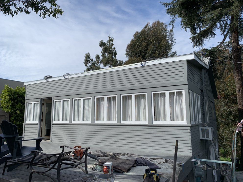 A small house with a lot of windows is being painted