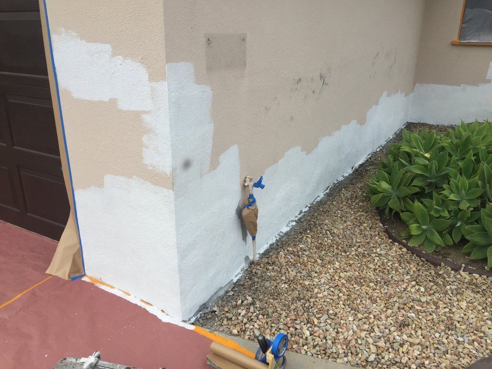 A white wall is being painted on the side of a house.