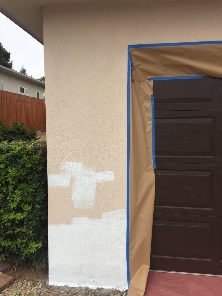 A brown garage door is being painted white