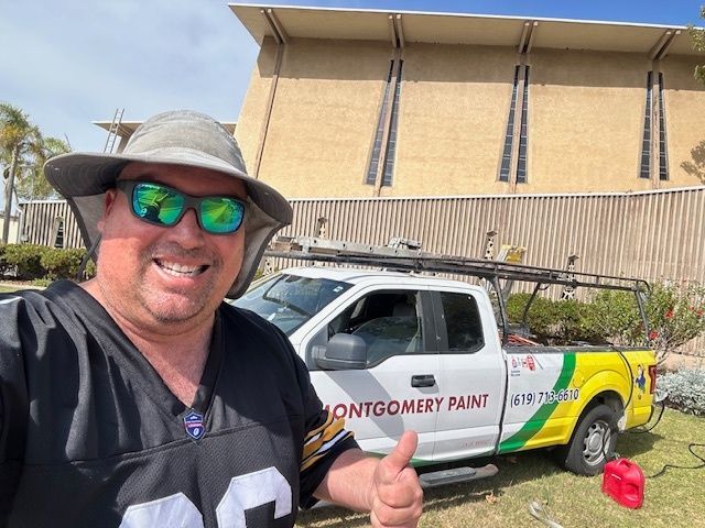 A man wearing a hat and sunglasses is giving a thumbs up in front of a truck.