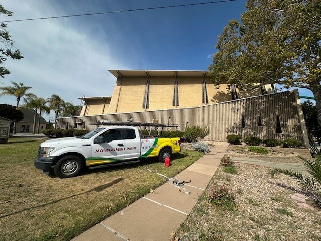 A white and yellow truck is parked in front of a building.
