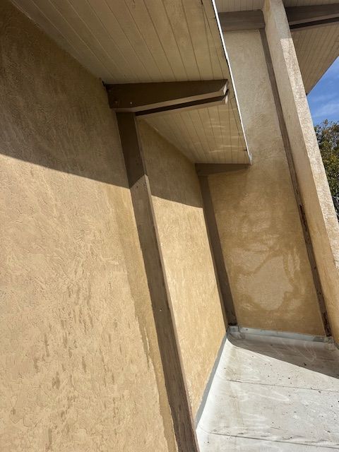 A corner of a building with a concrete walkway leading to it.