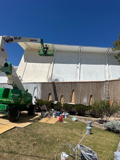 A crane is being used to paint the side of a building.