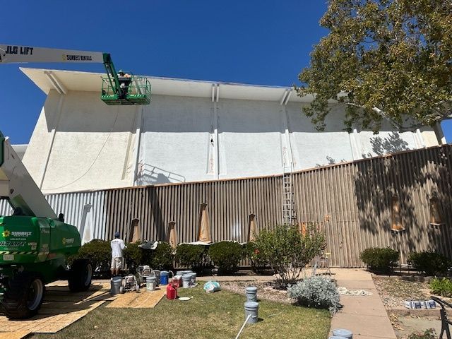 A crane is being used to paint the side of a building.