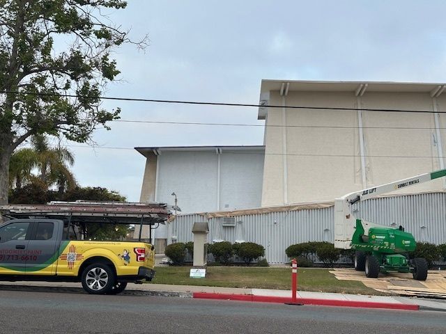 A yellow and green truck is parked in front of a building